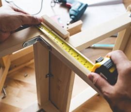 Man assembly wooden furniture,fixing or repairing house with yellow tape measures.